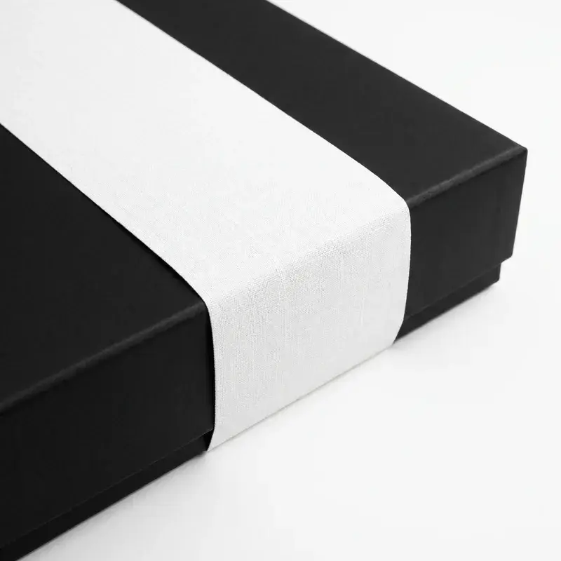 Black rectangular box wrapped with a wide white paper band.