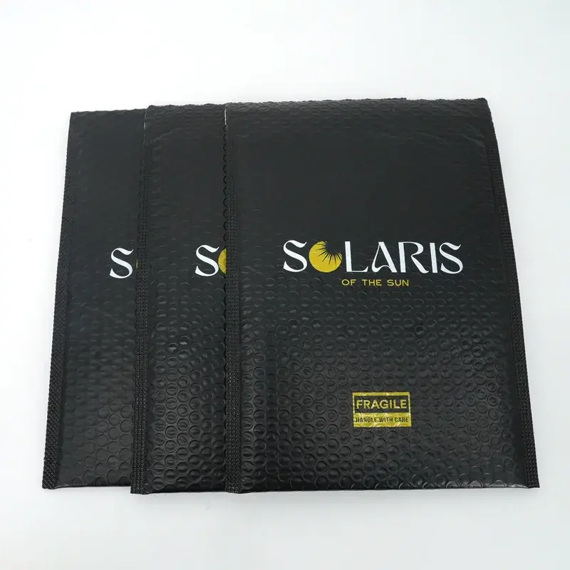 Overlapping black bubble mailers with gold and white lettering.