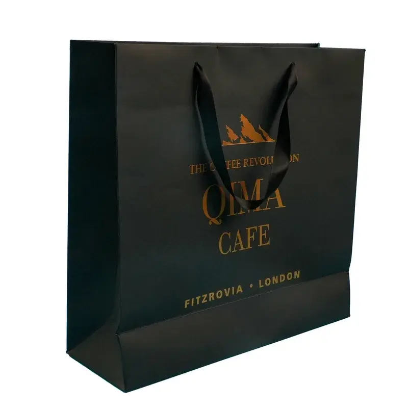 Black paper shopping bag with gold lettering and dark handles.