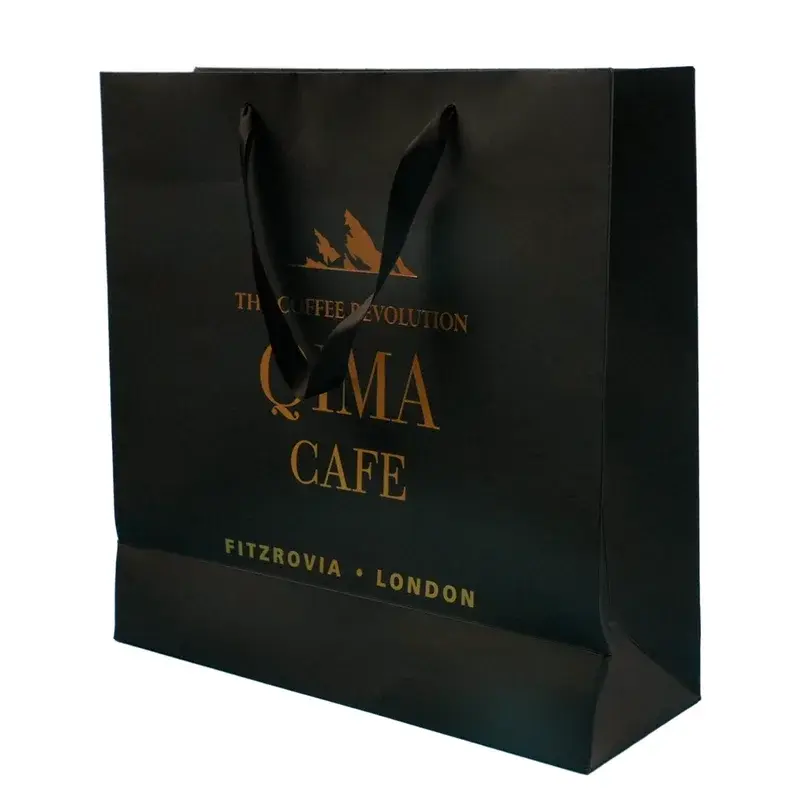 Black paper shopping bag with gold lettering and dark handles.