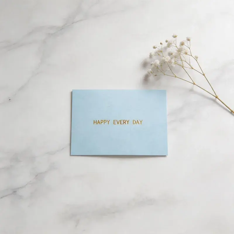 Pale blue message card beside a small dried flower stem.