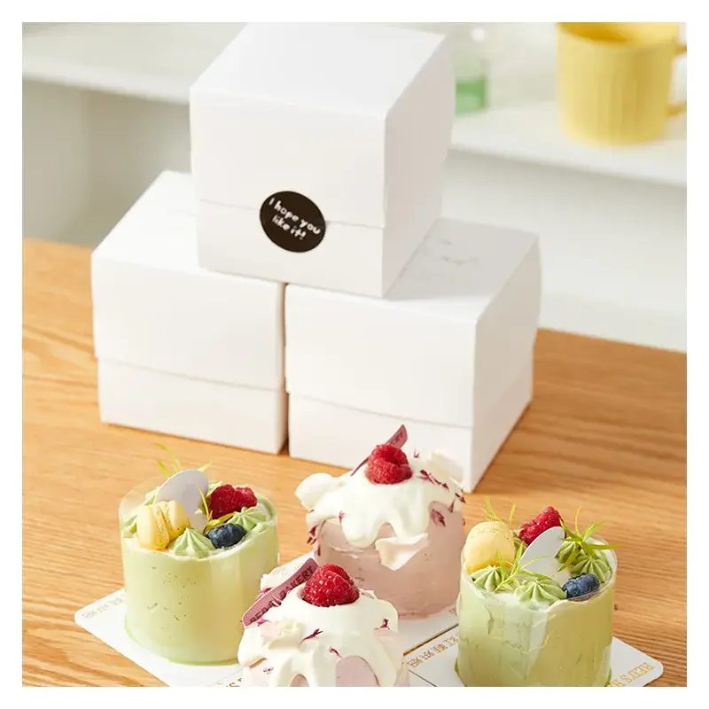 Decorated cakes in front of stacked white folding boxes.