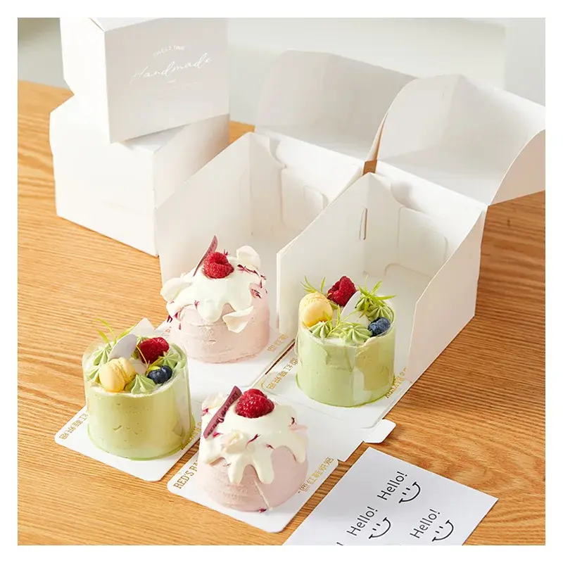 Small decorated cakes beside open white folding boxes.