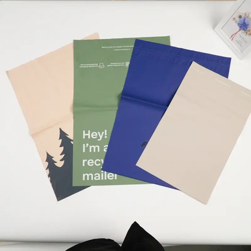 Overlapping green, blue and beige mailing bags laid flat.