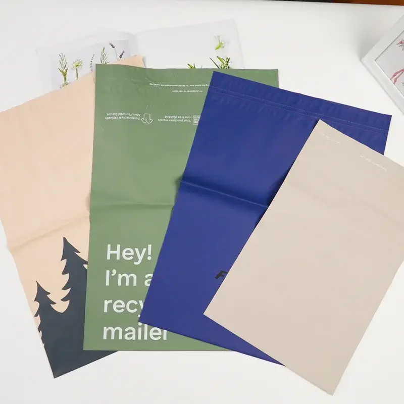 Green, blue and beige mailing bags arranged on a pale surface.