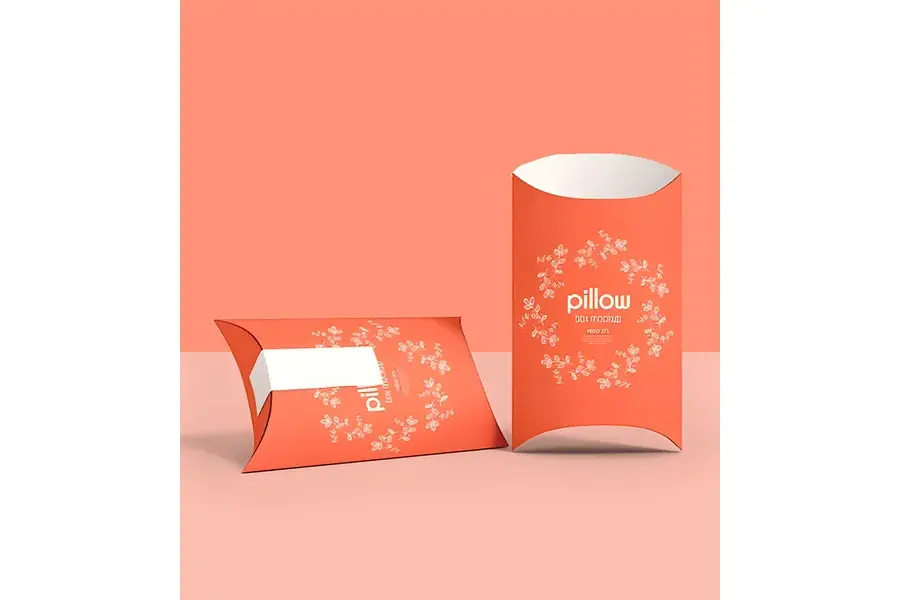 Two coral pillow boxes with white printing and curved ends.