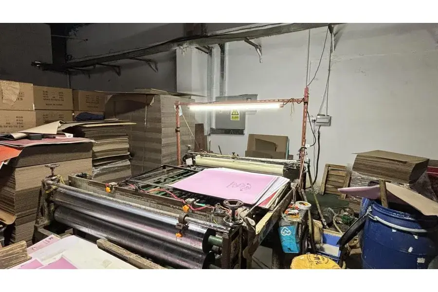 Printing equipment with a pink sheet in a factory workspace.