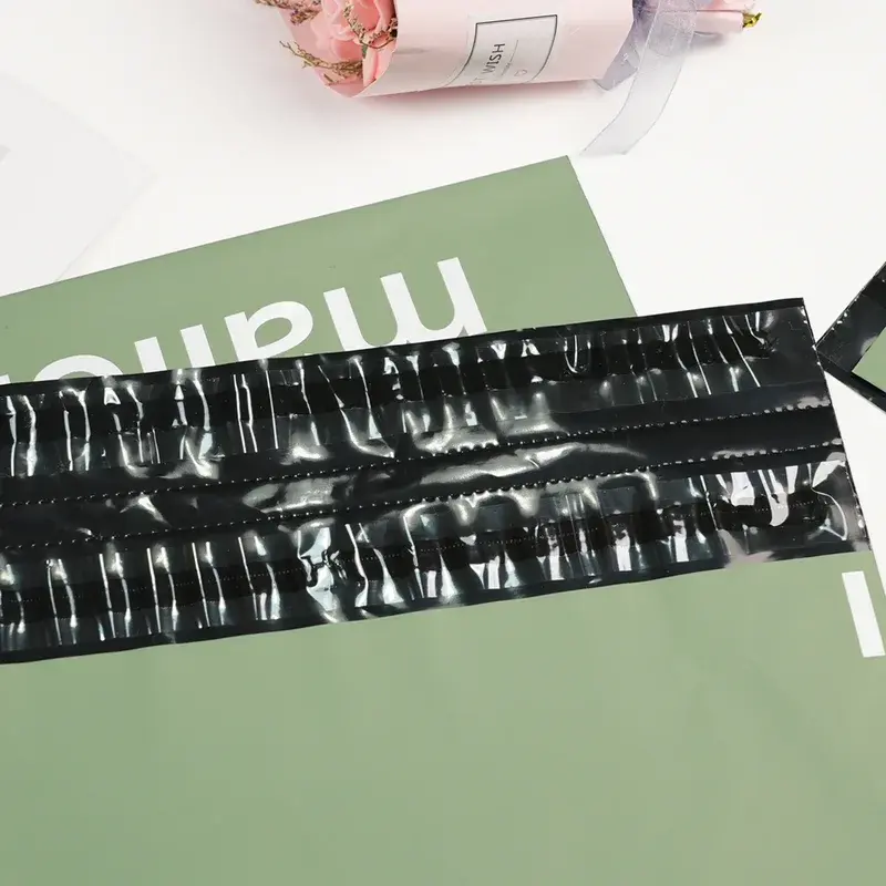 Close view of black adhesive strips on a green mailing bag.