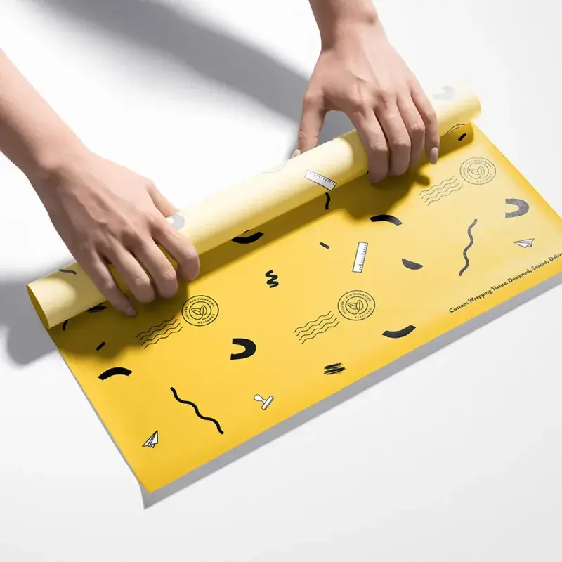Hands unrolling yellow paper with small black printed graphics.