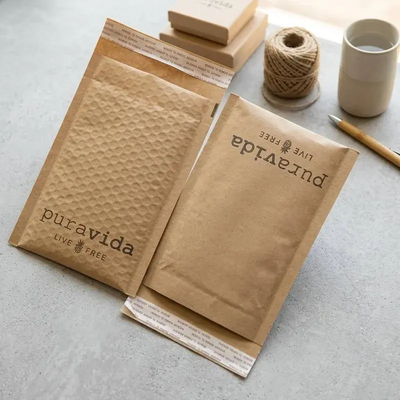 Kraft padded mailers beside small boxes, cord and a paper tube.