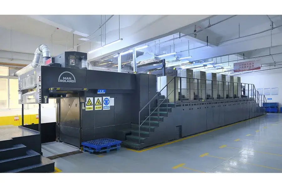 Large multi-unit printing press in a factory hall.