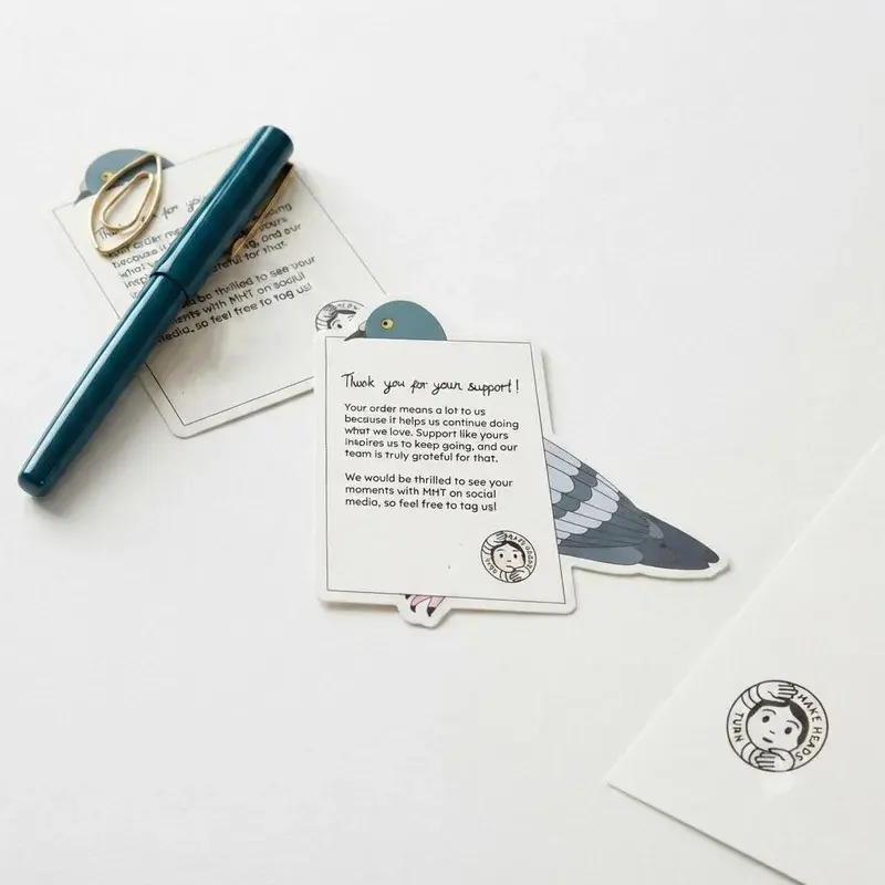 Pigeon-shaped card beside a pen and white envelope.