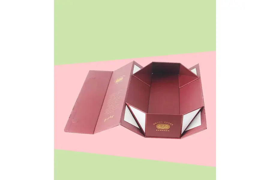 Pink folding box with multiple hinged panels opened outward.