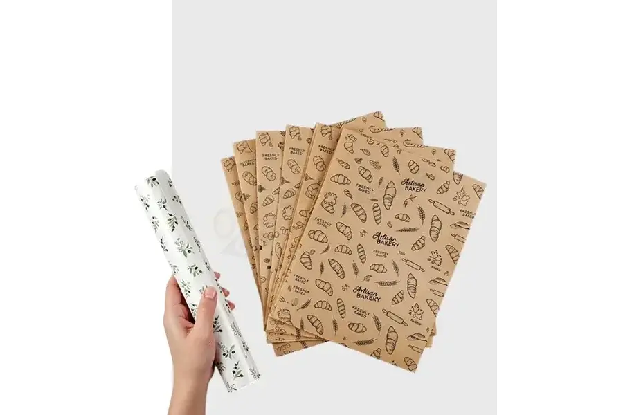 Hand holding a printed paper roll beside patterned kraft sheets.