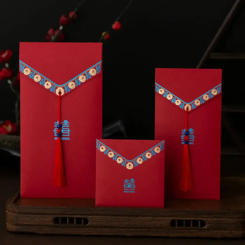 Three upright red envelopes with colorful trim and tassels.