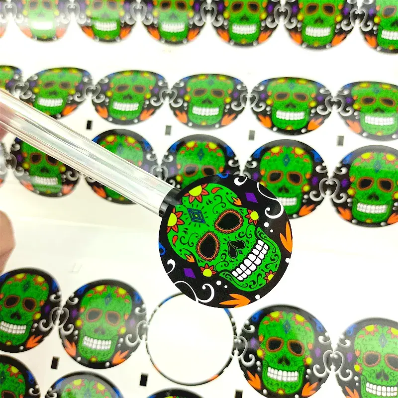 Round green printed sticker being peeled from its backing sheet.