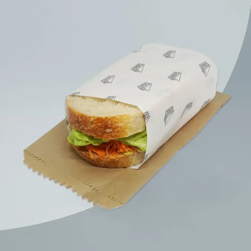 Sandwich partly wrapped in white printed paper.