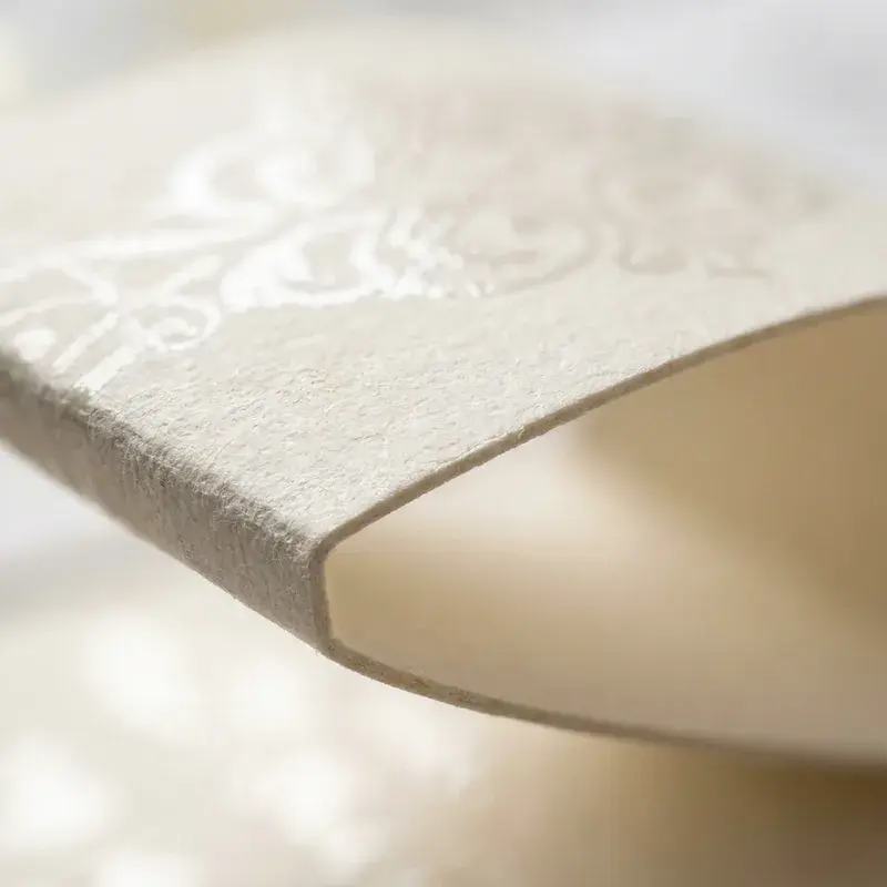 Close view of a curved cream sleeve with a textured pattern.