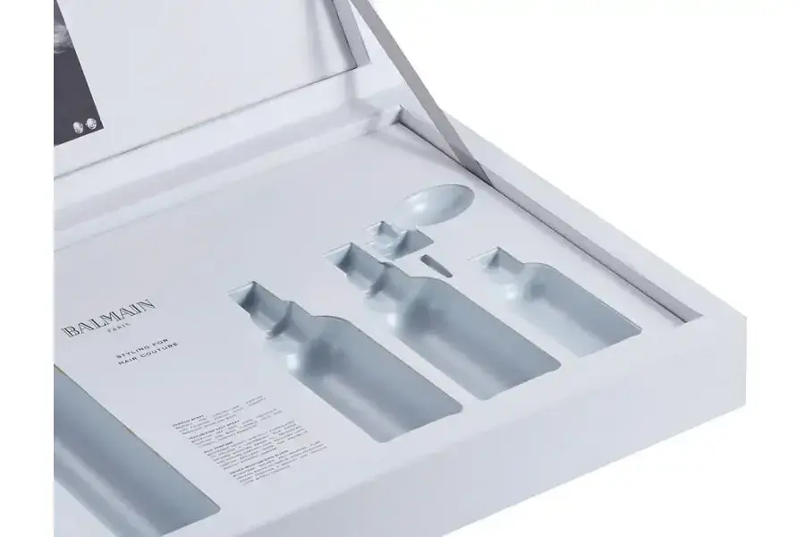 Open white presentation box with bottle-shaped insert cutouts.