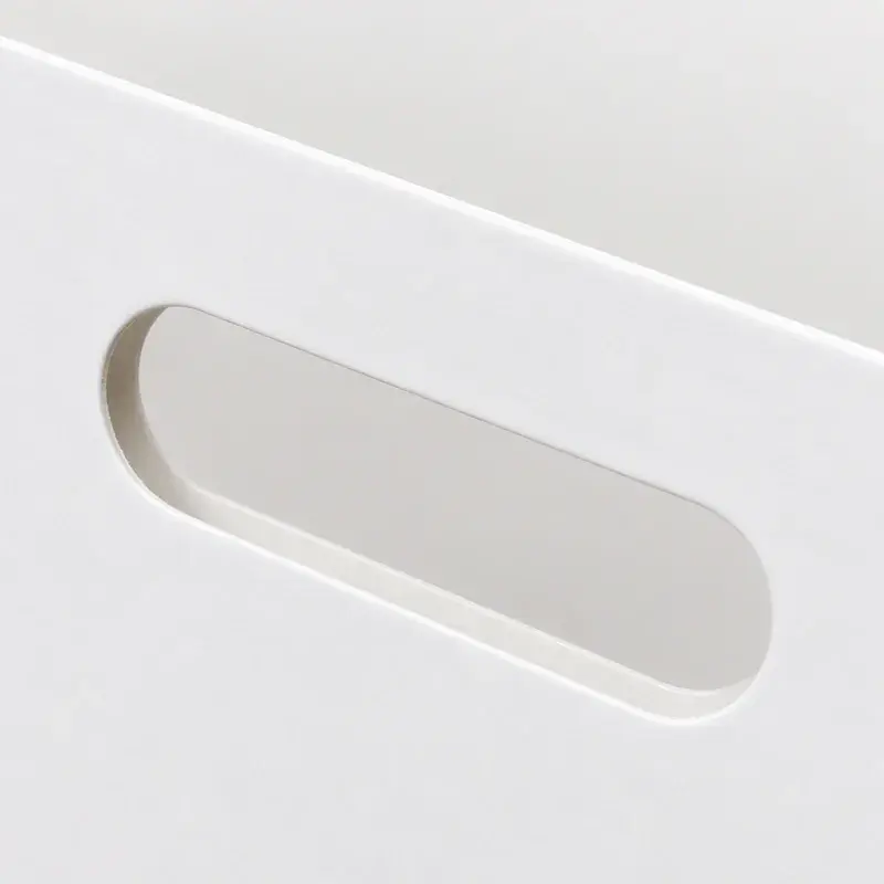 Close view of an oval handhold cut into a white box panel.
