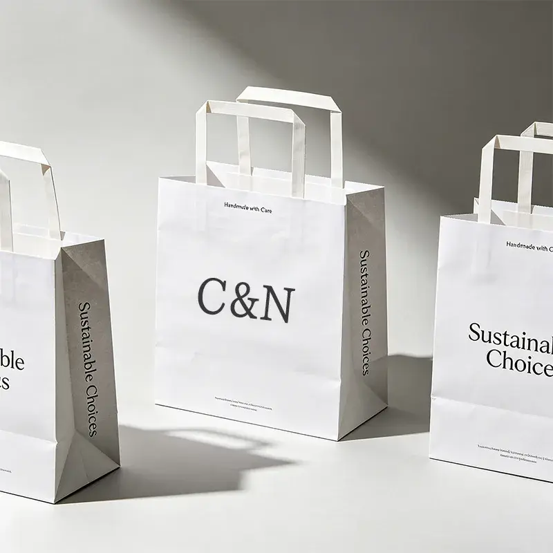 White paper bags with flat handles and black printed lettering.