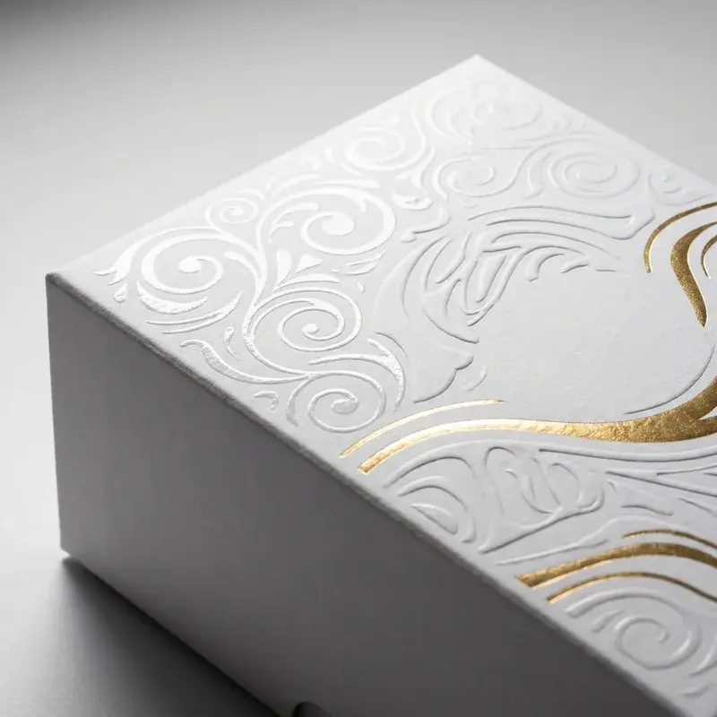 Close view of raised white patterns and gold-colored lines on a box.