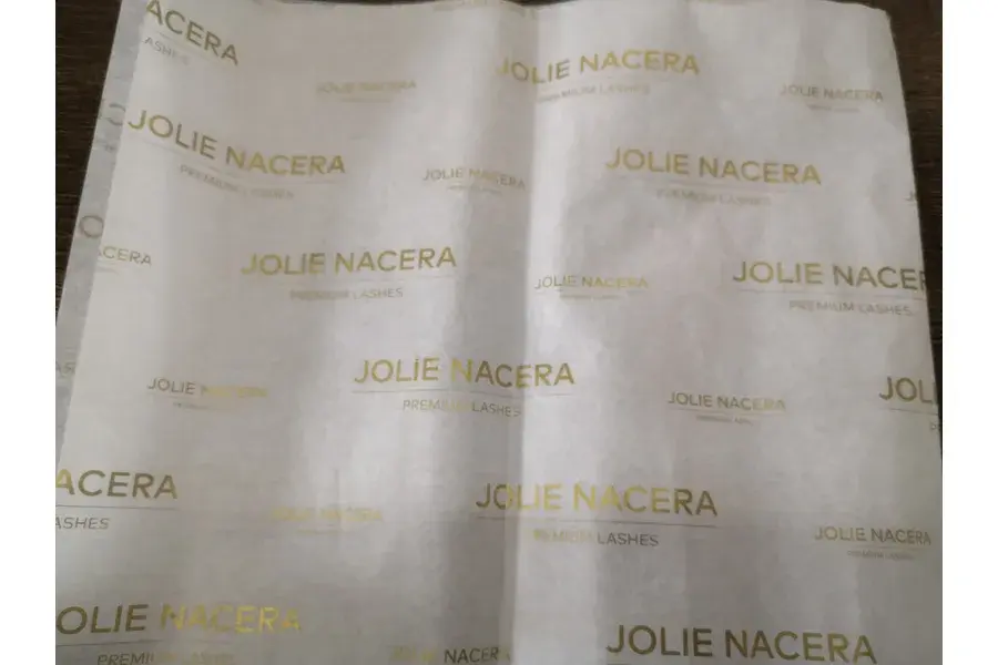 White tissue paper with repeating gold-colored lettering.
