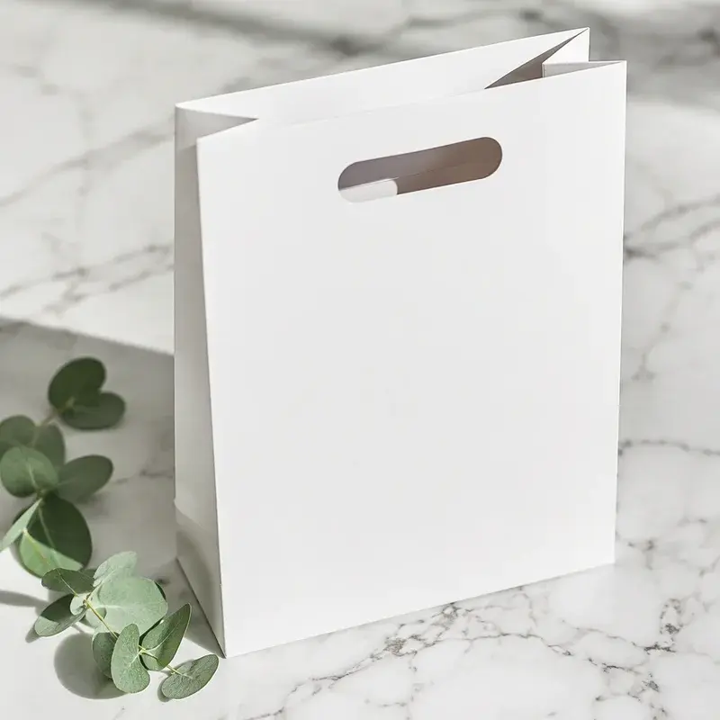 White paper bag with an oval cutout handle on a pale surface.