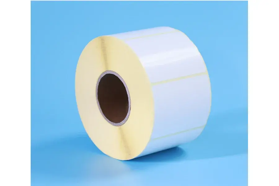 White blank label roll standing on a blue background.