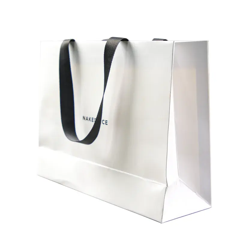 Angled view of a white paper bag with black ribbon handles.