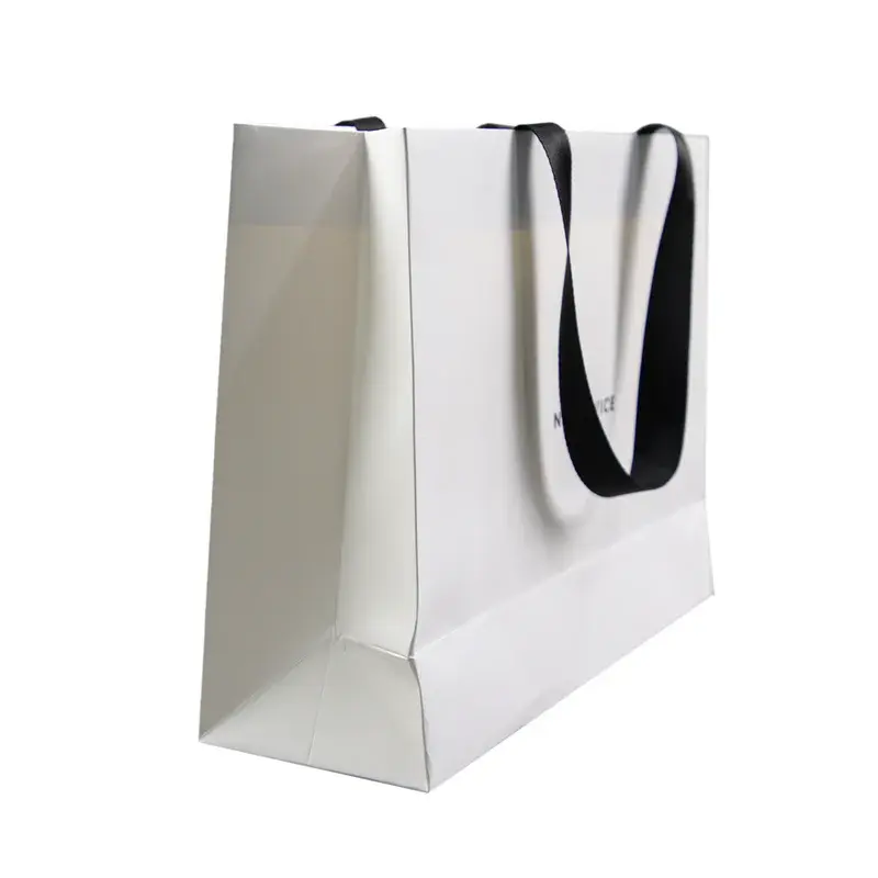 Side view of a white paper bag with black ribbon handles.