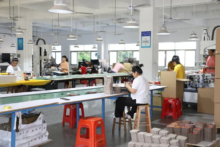 Workers seated at long tables in a bright production room.