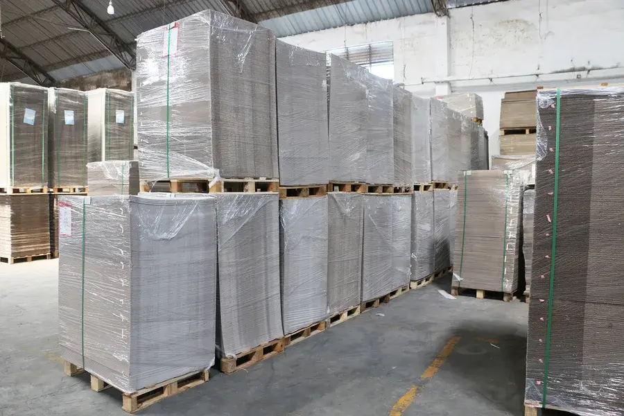 Tall wrapped stacks of cartons on pallets in a warehouse.